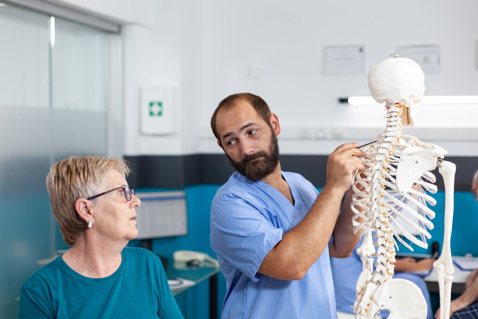 Woman and nurse looking at spinal cord on human skeleton