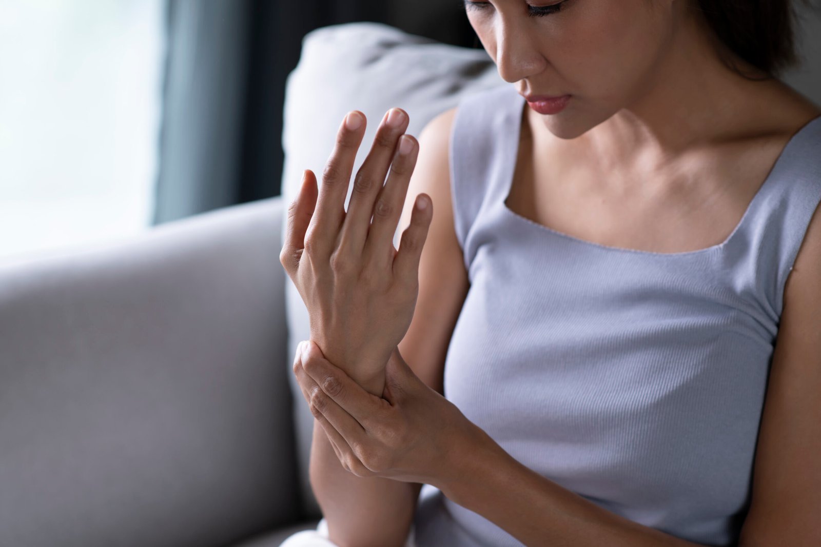 Young Asian woman wearing casual clothes suffering pain on hands and fingers, arthritis inflammation. Woman has pain in wrist. Health care and medical concept.