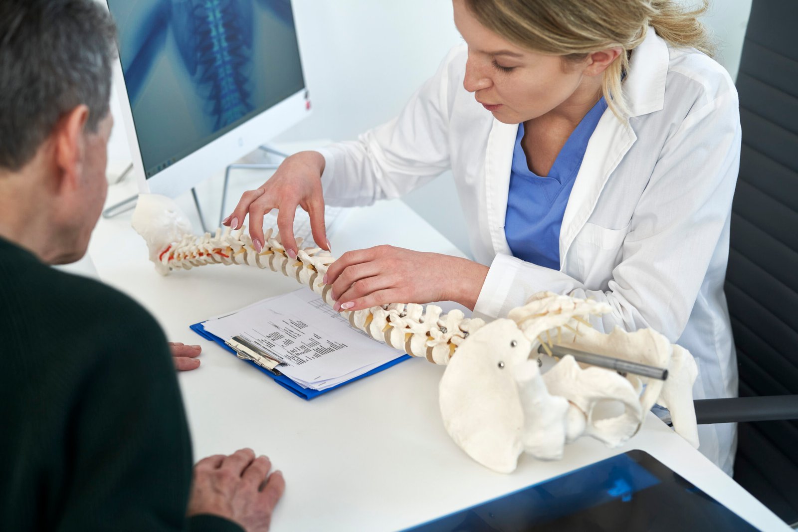 Caucasian senior man with female doctor talking about spine at the office