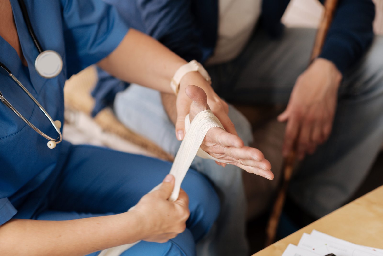 Special tie. Observant competent medical worker paying a visit and applying elastic bondage while making elderly man feeling better