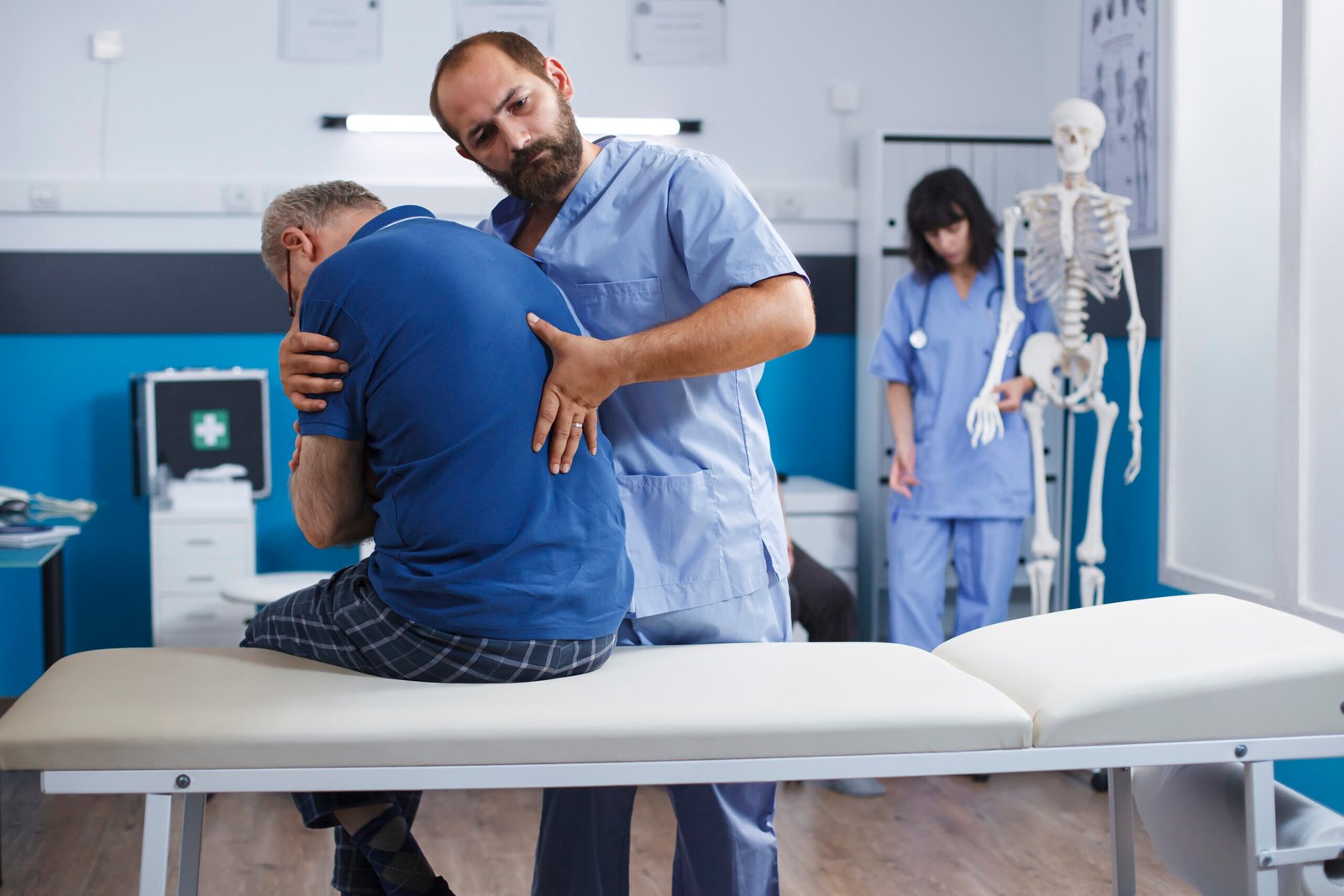 Osteopathic nurse gently extends spine of elderly patient with injury as part of physiotherapy. Chiropractor provides aid to gentleman experiencing back pains, aiding in physical recovery.