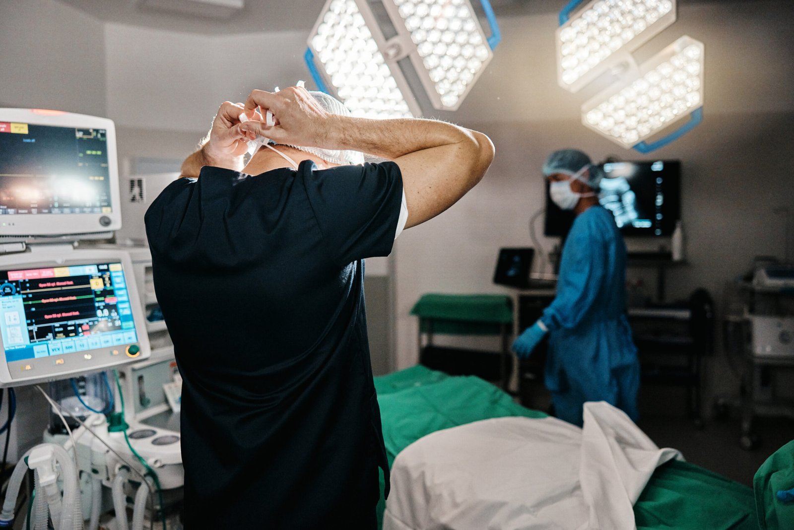 Surgery, healthcare or doctor with mask in operating room, theater or trauma unit for anatomy emergency. Medical, ppe or man surgeon at hospital with uniform, check or safety for clinician compliance.