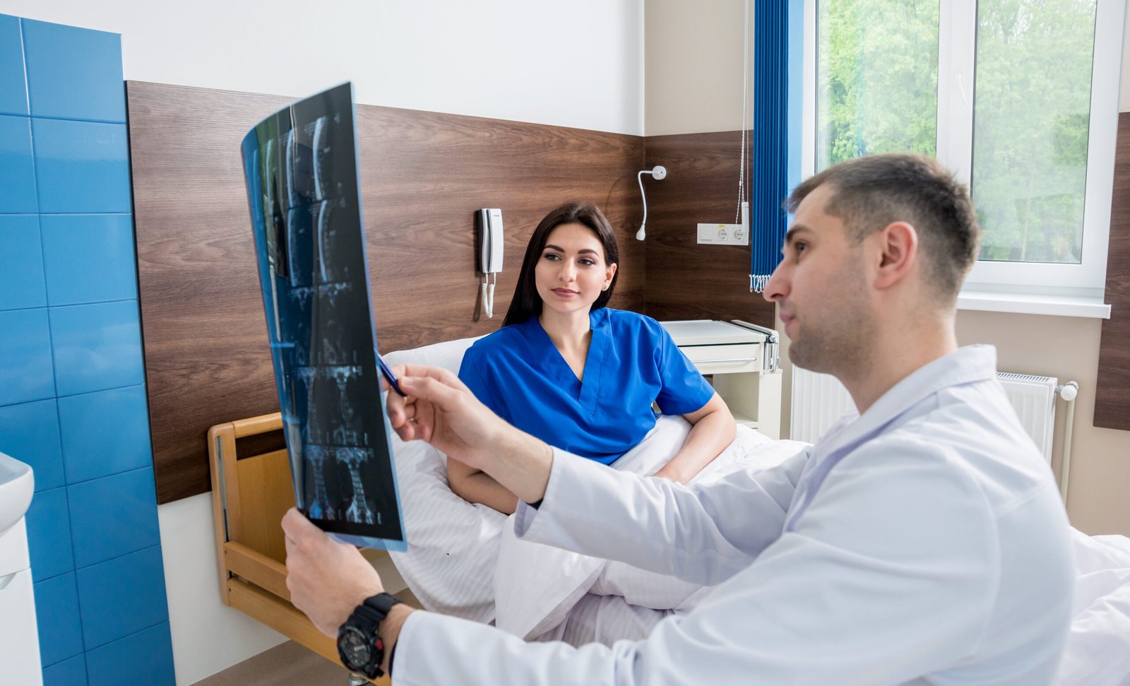 Traumatologist showing MRI film to patient in hospital. Medical background