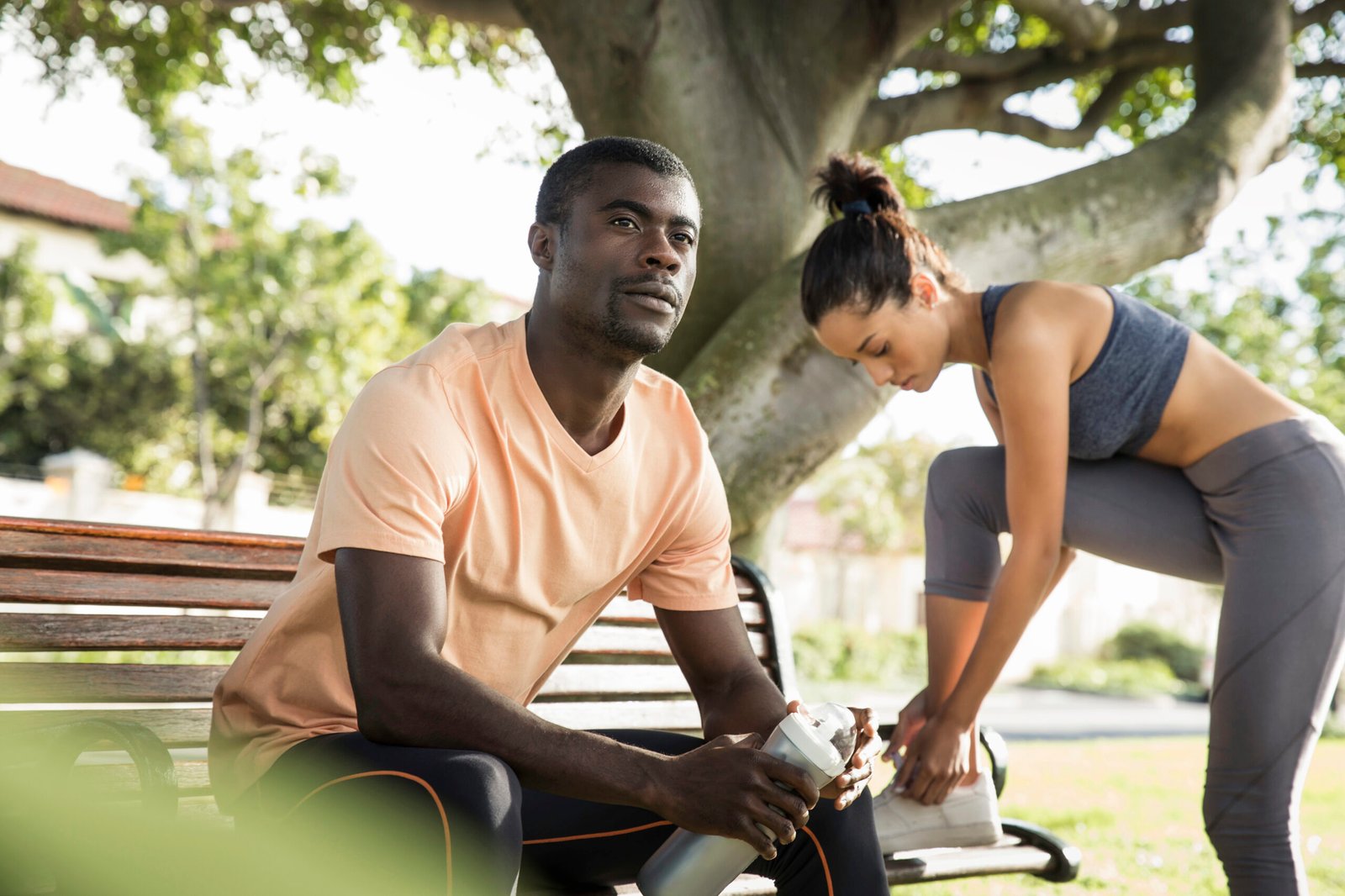 Man wearing sports clothes sitting on park bench looking away